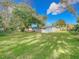 Spacious backyard with lush green grass, mature trees and foliage with a partial view of the back of the house at 444 Sunnyview Cir, Orlando, FL 32810