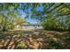 View of the gray home's backyard through trees showing windows and outdoor space at 5206 Cortez Dr, Orlando, FL 32808