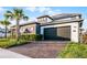 A two-story home with a gray two-car garage, solar panels, and attractive landscaping with a brick paver driveway at 6439 Trailblaze Bnd, St Cloud, FL 34771