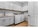 Bright laundry room features white cabinets, quartz counters, subway tile backsplash, and modern washer and dryer at 6439 Trailblaze Bnd, St Cloud, FL 34771