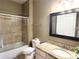 Bathroom featuring shower with sliding glass door, toilet, vanity with granite top and black framed mirror at 6575 Time Square Ave # 101, Orlando, FL 32835
