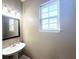 Neutral-toned bathroom with a pedestal sink, stylish lighting, and a large window at 6575 Time Square Ave # 101, Orlando, FL 32835