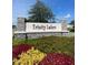 Stone entrance sign to Trinity Lakes, accented with colorful flower beds, showcasing the community's welcoming curb appeal at 7264 Dilly Lake Ave, Groveland, FL 34736