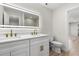 Modern bathroom with double sinks, a large illuminated mirror, white cabinets, and a glimpse of a glass-enclosed shower at 7320 Fieldcrest Ave, Winter Park, FL 32792