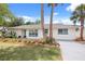 Front exterior view of a white home with stone accents, manicured landscaping, and palm trees at 7320 Fieldcrest Ave, Winter Park, FL 32792