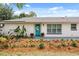 Close up of the front of the house, featuring a bright turquoise door and meticulously maintained landscaping at 7320 Fieldcrest Ave, Winter Park, FL 32792