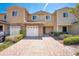 Front exterior view of a tan and yellow townhouse with a brick paved driveway at 10124 Shadow Leaf Ct, Orlando, FL 32825