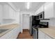Galley kitchen featuring modern black appliances, white cabinets and wood-look flooring at 1013 S Hiawassee Rd # 3628, Orlando, FL 32835