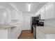 Galley kitchen featuring modern black appliances, and bright white cabinetry with wood-look flooring at 1013 S Hiawassee Rd # 3628, Orlando, FL 32835