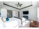 Large primary bedroom featuring tray ceilings, an entertainment center and sliding barn doors to ensuite bathroom at 10255 Beechwood Ln, Orlando, FL 32832