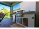 A fully equipped outdoor kitchen featuring a grill and mini-refrigerator is ready for your culinary creations at 10255 Beechwood Ln, Orlando, FL 32832
