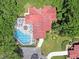 Aerial shot of a red-roofed home with a screened-in pool, lush landscaping and long driveways at 112 Coventry Ln, Haines City, FL 33844