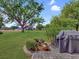 Backyard features brick patio, large shade tree, lush landscaping and a barbecue at 112 Coventry Ln, Haines City, FL 33844