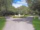 Community entrance featuring lush greenery, an American flag, and landscaped traffic circle at 112 Coventry Ln, Haines City, FL 33844