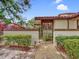 View of the home's gate entrance and walkway with clay tile roof, privacy wall, and lush bushes at 112 Coventry Ln, Haines City, FL 33844