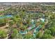 Aerial view showing the community lazy river, pool, and tennis courts surrounded by trees at 1158 Oak Bluff Dr, Davenport, FL 33837