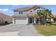 Beautiful two-story home featuring a well-manicured lawn, neutral color palette, and a paved driveway leading to a two-car garage at 1158 Oak Bluff Dr, Davenport, FL 33837