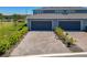 View of townhome exterior with brick driveways, two car garage and manicured landscaping at 14432 Orchid Island Dr, Orlando, FL 32827