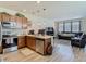 Open concept kitchen with stainless appliances, wood cabinets and adjacent living room with leather sofas at 14432 Orchid Island Dr, Orlando, FL 32827