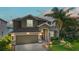 Charming two-story home with a two-car garage, stone accents, manicured landscaping and a beautiful dusk sky at 1628 Thetford Cir, Orlando, FL 32824