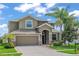 Charming two-story home features a well-manicured lawn, mature palm trees, and an attached two-car garage at 1628 Thetford Cir, Orlando, FL 32824