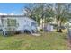 View of the backyard with a well-maintained lawn and white siding house with a small deck at 18302 15Th Ave, Orlando, FL 32833