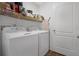 Bright laundry room featuring a white washer and dryer with shelving and a door at 1924 Piedmont Ct, Mascotte, FL 34753