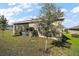 A serene backyard featuring a cozy, screened patio and lush green grass, enhanced by a mature tree at 2451 Spring Breeze Dr, Leesburg, FL 34748