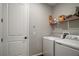 Laundry room with washer and dryer, shelf with supplies, and white door at 2451 Spring Breeze Dr, Leesburg, FL 34748