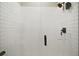 Shower featuring horizontally stacked white tiling, rainfall shower head, and black hardware at 2451 Spring Breeze Dr, Leesburg, FL 34748