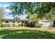 Charming single-story home featuring a manicured lawn, brick accents, attached two-car garage, and mature trees at 2545 Dellwood Dr, Orlando, FL 32806