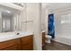 Bright bathroom with wood cabinets, long mirror, and a shower/tub with blue curtain at 2624 Lodi Cir # 101, Kissimmee, FL 34746
