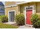 Inviting townhome entrance features a red front door, green bushes with red blooms, and a cozy welcome mat at 2624 Lodi Cir # 101, Kissimmee, FL 34746
