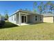 Backyard featuring a covered patio with a ceiling fan, a sliding glass door, and lush green lawn at 3437 Possehl Pl, The Villages, FL 32163