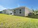 Lush backyard showcasing the home's siding, covered patio, and green lawn extending to the back at 3437 Possehl Pl, The Villages, FL 32163