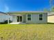 Exterior view of the house from the backyard, showcasing a covered patio and well-kept lawn at 3437 Possehl Pl, The Villages, FL 32163