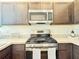 This kitchen features stainless steel appliances, stone countertops, and rich wood cabinets at 3437 Possehl Pl, The Villages, FL 32163