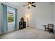 Bright bedroom with carpet, a ceiling fan, and a window with blue curtains overlooking lush greenery at 3893 Wind Dancer Cir, St Cloud, FL 34772