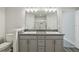Bathroom with double sinks, granite countertops, gray cabinets, toilet, and a large mirror at 442 Big Black Pl, Kissimmee, FL 34759