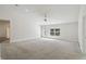 Spacious living room with a ceiling fan, large window, glass door, and neutral carpeting at 442 Big Black Pl, Kissimmee, FL 34759