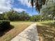 A view of the community park with lush trees, a pathway, and well maintained grass at 4730 Capital Blvd, St Cloud, FL 34769