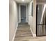 Hallway with grey plank floors leading to additional rooms with a stainless refrigerator at the end at 5237 Davisson Ave, Orlando, FL 32810