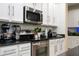 Close-up of stainless steel appliances and white cabinets in the kitchen with tile backsplash at 6008 Golden Dewdrop Trl, Windermere, FL 34786