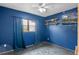 A bright bedroom showcases blue walls, a ceiling fan, and a window with blue curtains, offering a cozy and private space at 6031 W Ridgewood Ave, Orlando, FL 32835