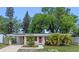 Charming single-story home with a well-manicured lawn, mature trees, and a welcoming red front door at 6031 W Ridgewood Ave, Orlando, FL 32835