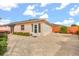 Rear exterior view of the house featuring a paved patio, enclosed sunroom and manicured landscaping at 613 Nuevo Leon Ln, The Villages, FL 32159