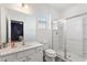 Well-lit bathroom features a glass-enclosed shower, a wide mirror and a toilet at 7012 Oakwood St, Davenport, FL 33837