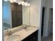 Elegant bathroom featuring double sinks, a granite countertop, and modern lighting fixtures at 725 Ginger Dr, Haines City, FL 33844