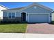 Charming single-story home featuring a two-car garage, brick driveway, and well-manicured lawn at 725 Ginger Dr, Haines City, FL 33844