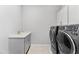 A fully-equipped laundry room with a sink and gray front-loading washing machine and dryer at 7633 Agrigento St, Clermont, FL 34714